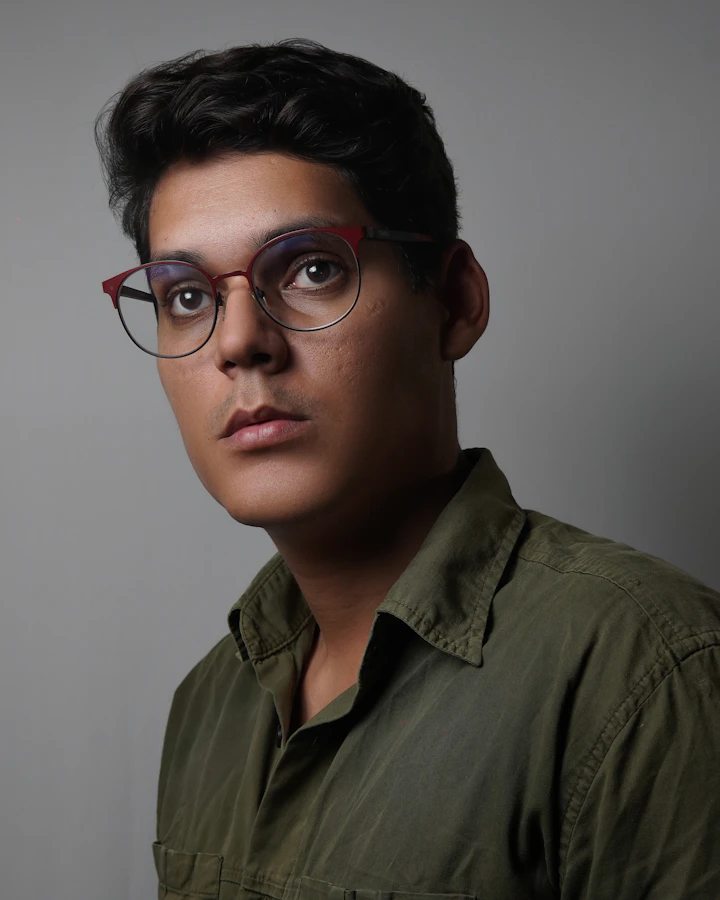 Homem de óculos e camisa, com olhar atento e pensativo