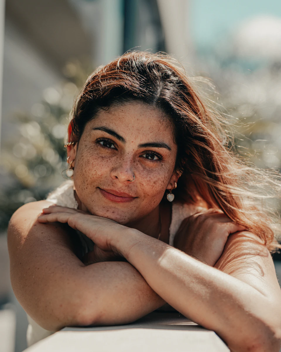 Mulher apoiada no parapeito, pensativa, com um leve sorriso